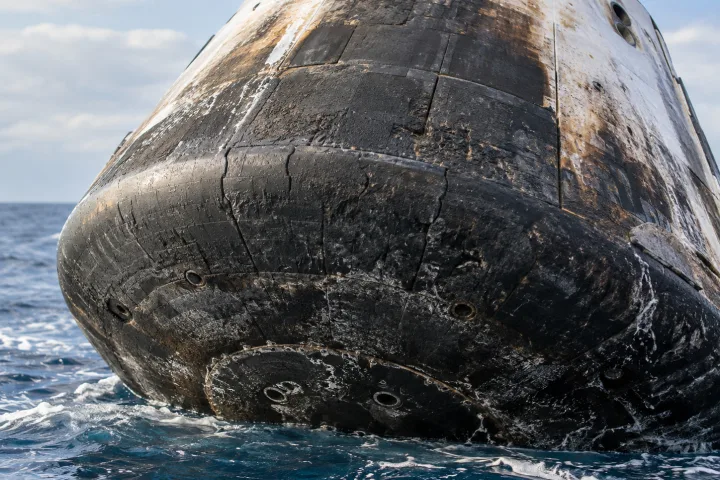 Una capsula spaziale che rientra nell'atmosfera circondata da un bagliore arancione di plasma